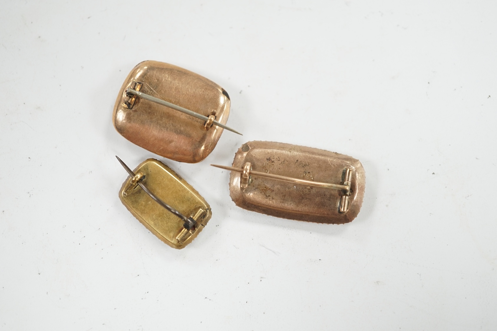 Three assorted 19th century yellow metal and seed pearl set mourning brooches, two with plaited hair beneath a glazed panel, largest 27mm. Condition - poor to fair